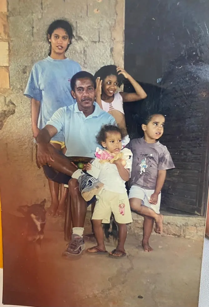 Rosângela na infância, em frente à casa simples da família