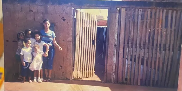 A família de Rosângela junto ao portão de madeira da casa